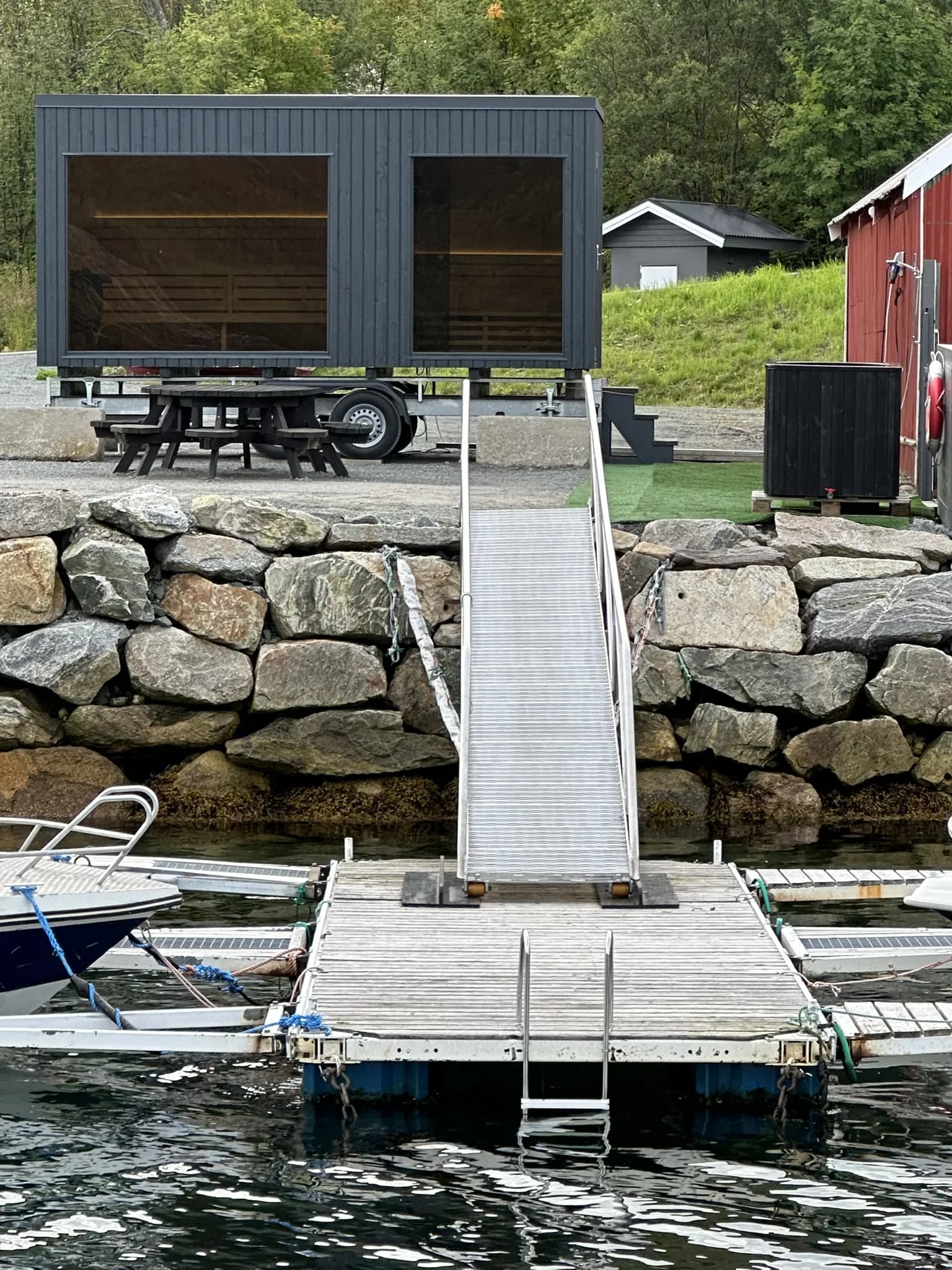 Badstuen sett fra utsiden med fjord og fjell i bakgrunnen