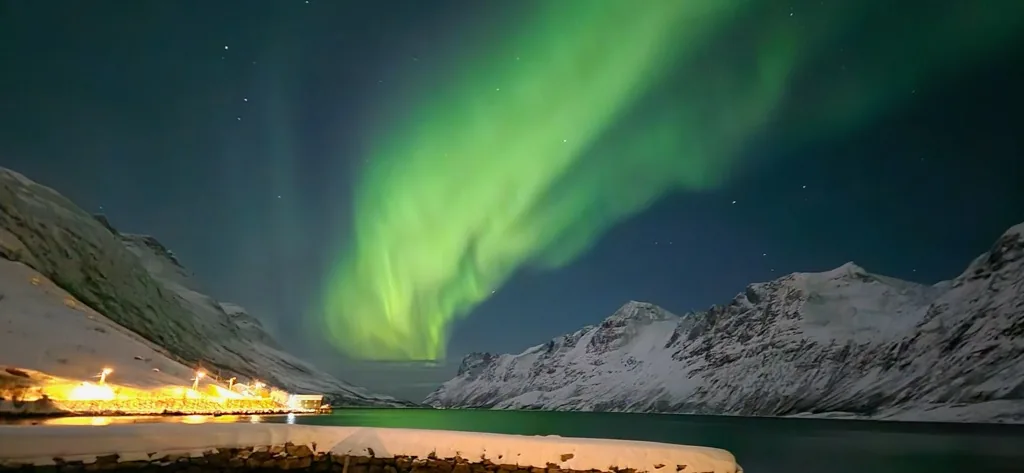 Nordlys speiler seg i fjorden en klar vinternatt