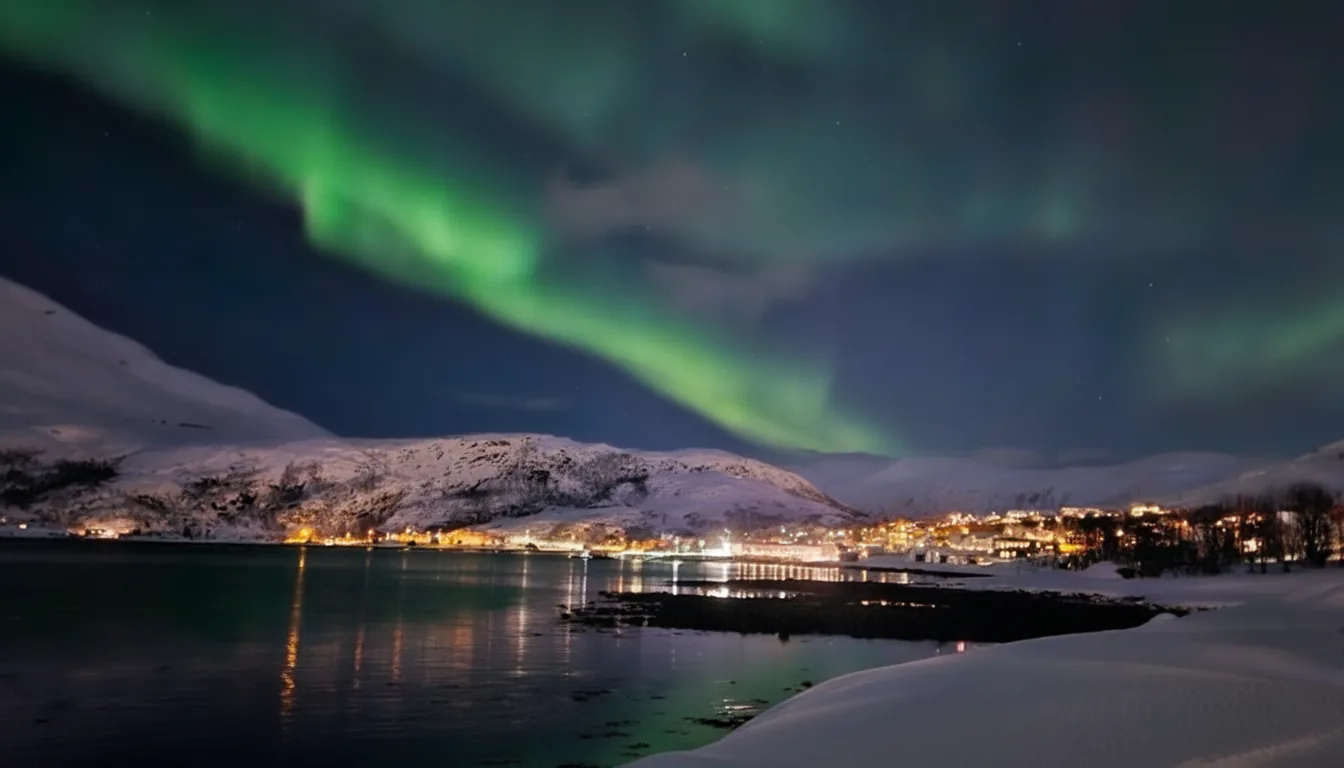 Ersfjordbotn om natten med grønt nordlys over fjorden og snødekte fjell